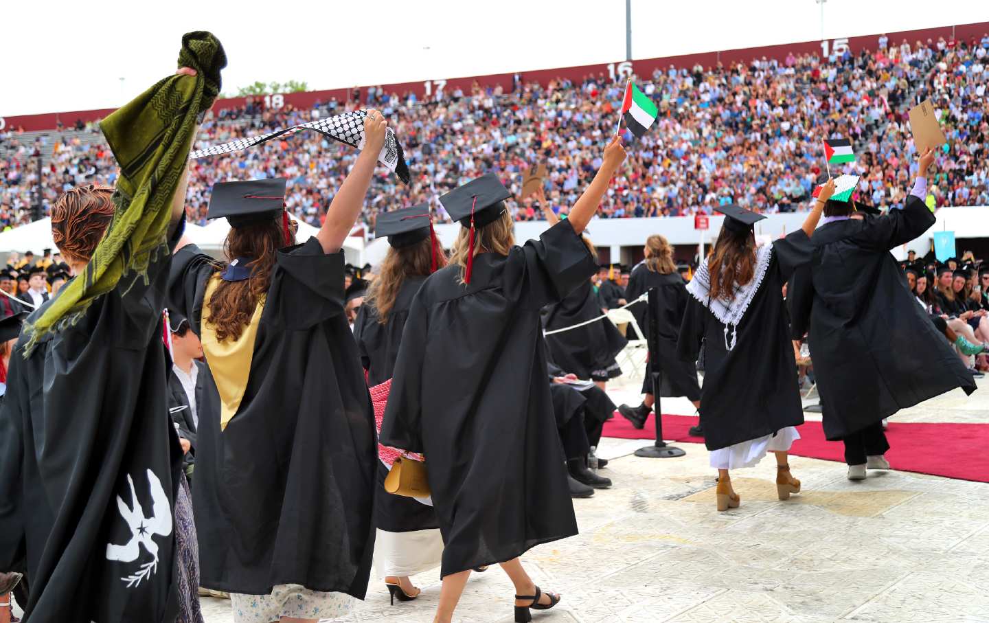 Students holding Palestinian flags and signs walk out of the UMass Amherst commencement ceremony in protest on May 18, 2024, as Chancellor Javier Reyes takes the stage to speak.