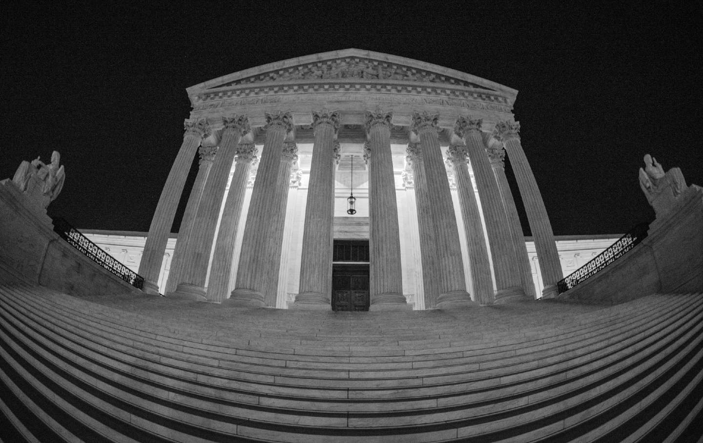 The US Supreme Court Building at night.
