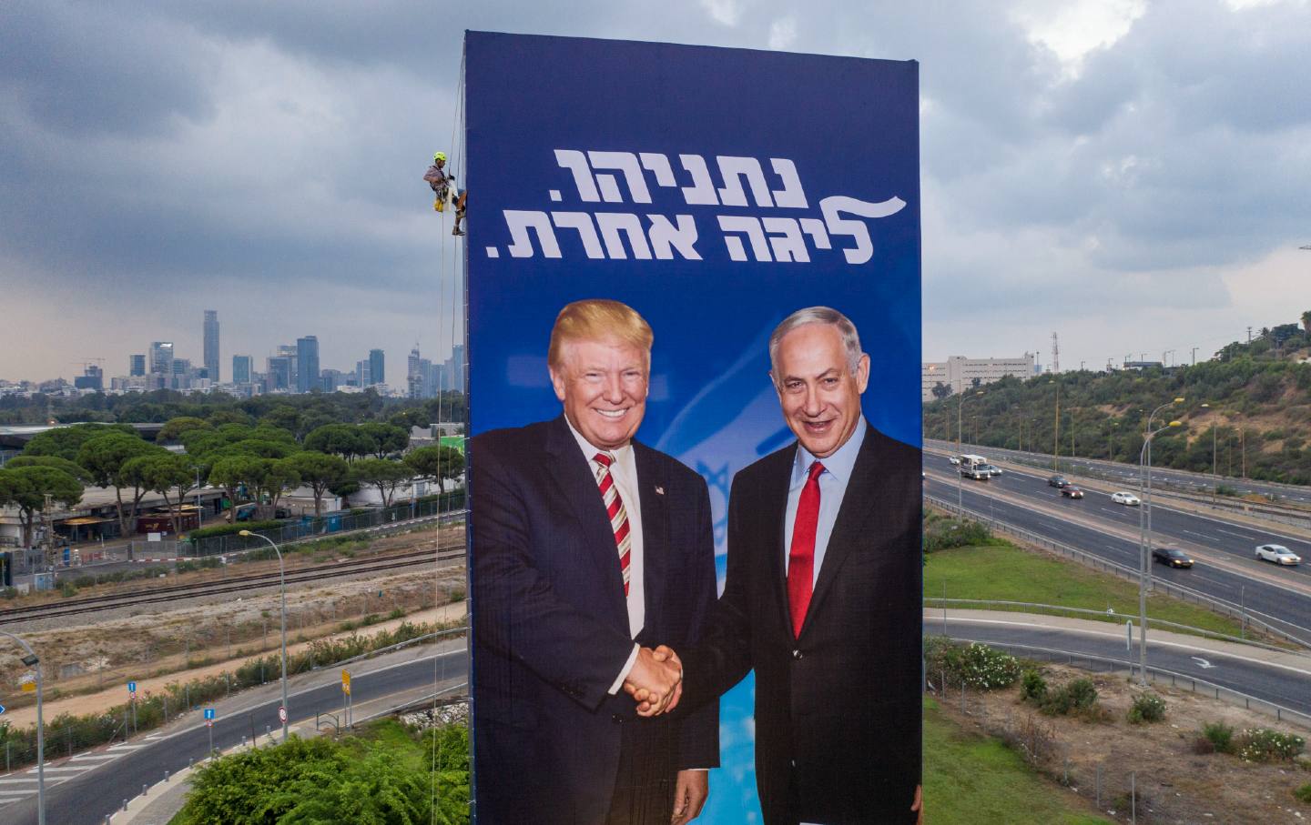 A worker hangs an election campaign billboard of the Likud party showing former US President Donald Trump, left, and Israeli Prime Minister Benjamin Netanyahu in Tel Aviv on September 8, 2019.