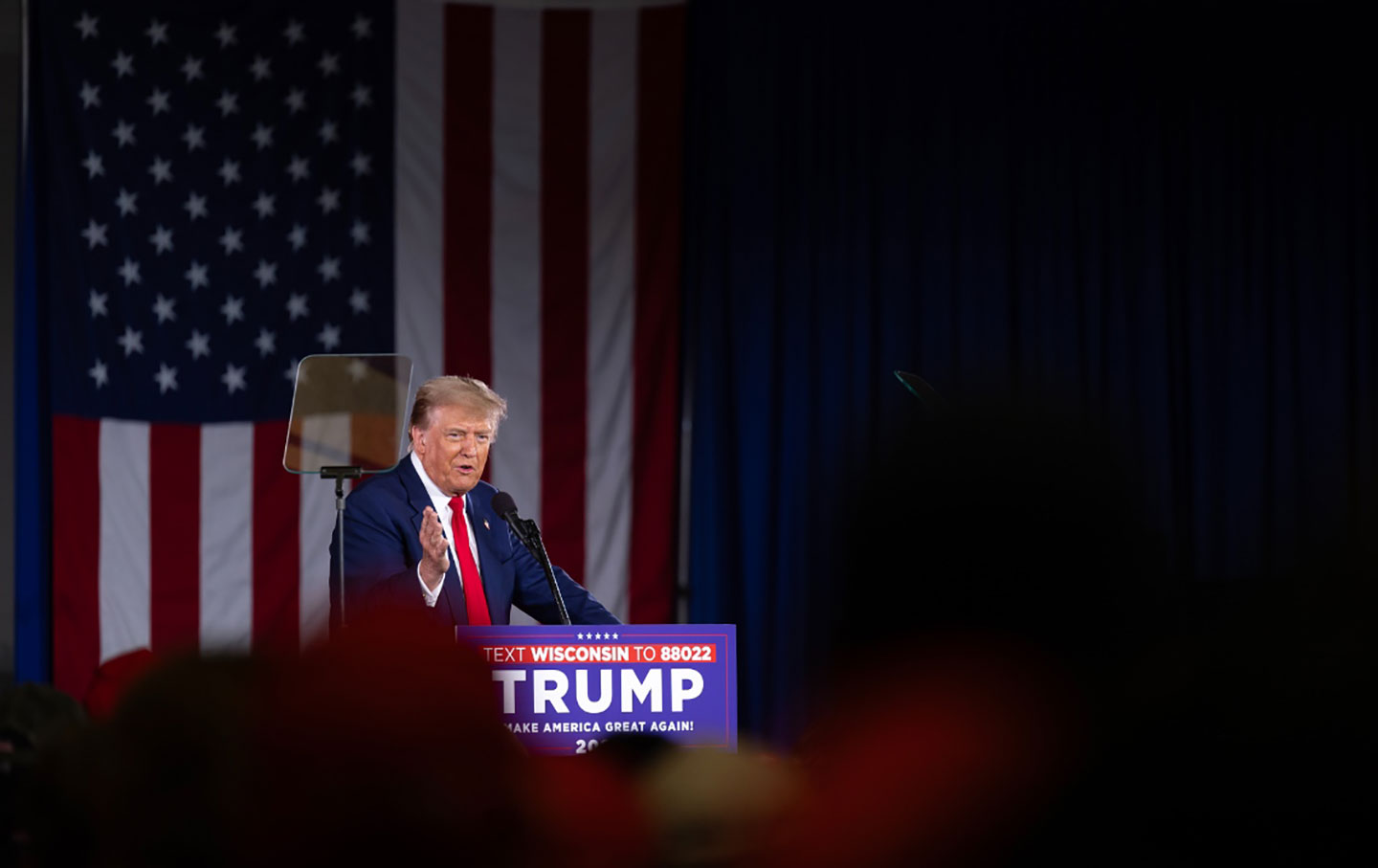 Donald Trump at a podium in front of an American flag.