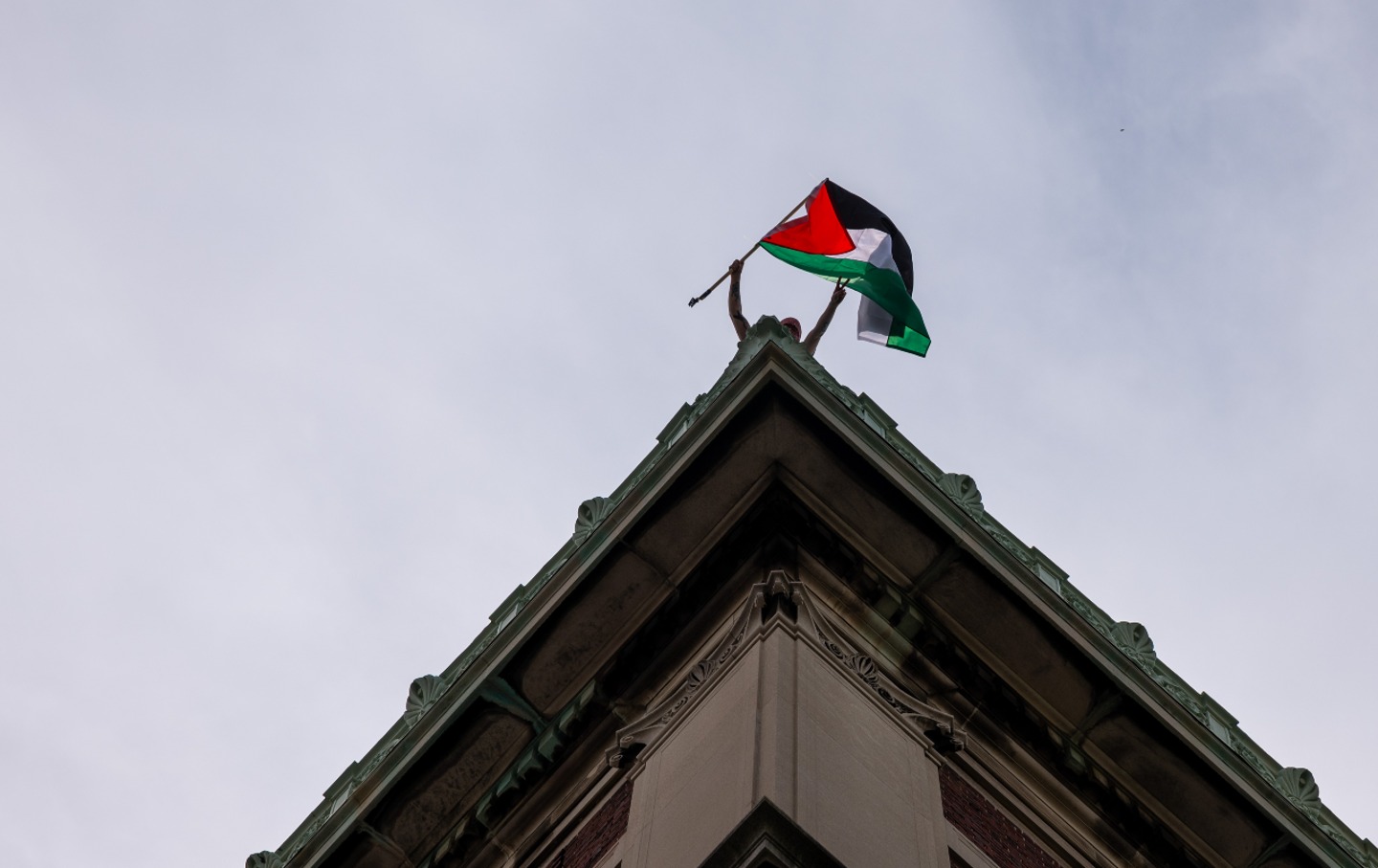A protester waves a Palestinian flag from the roof of Hamilton Hall at Columbia University on April 30, 2024.