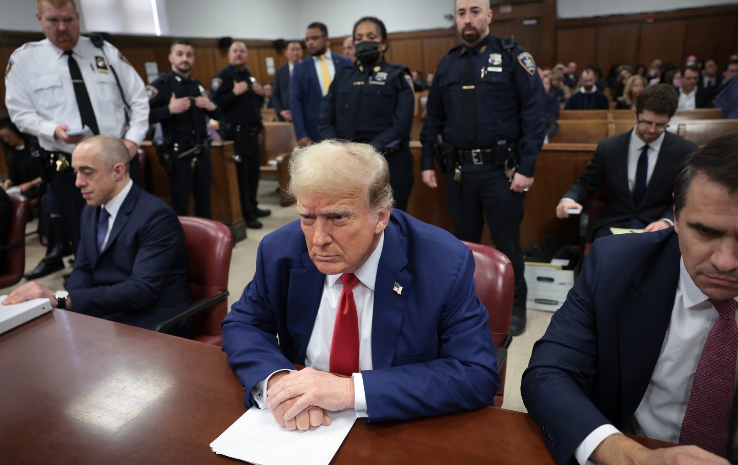 Donald Trump in court sitting at the defendant's table, flanked by his lawyers.