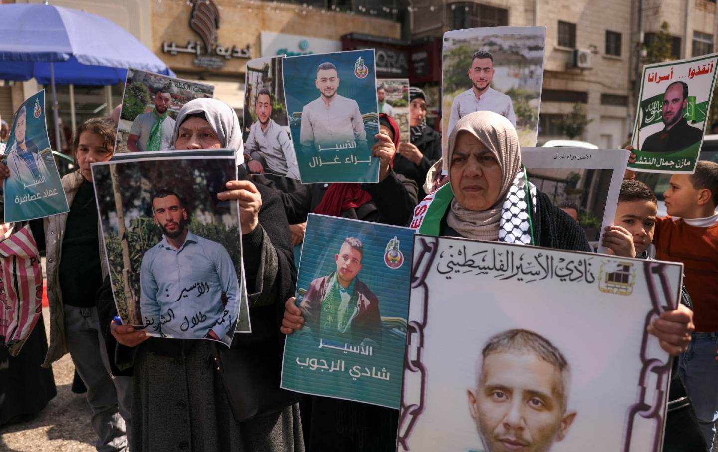 Relatives and friends of Palestinians imprisoned in Israel lift signs at a rally calling for their release and the return of the bodies of those who died during incarceration, in Hebron in the occupied West Bank on February 27, 2024.