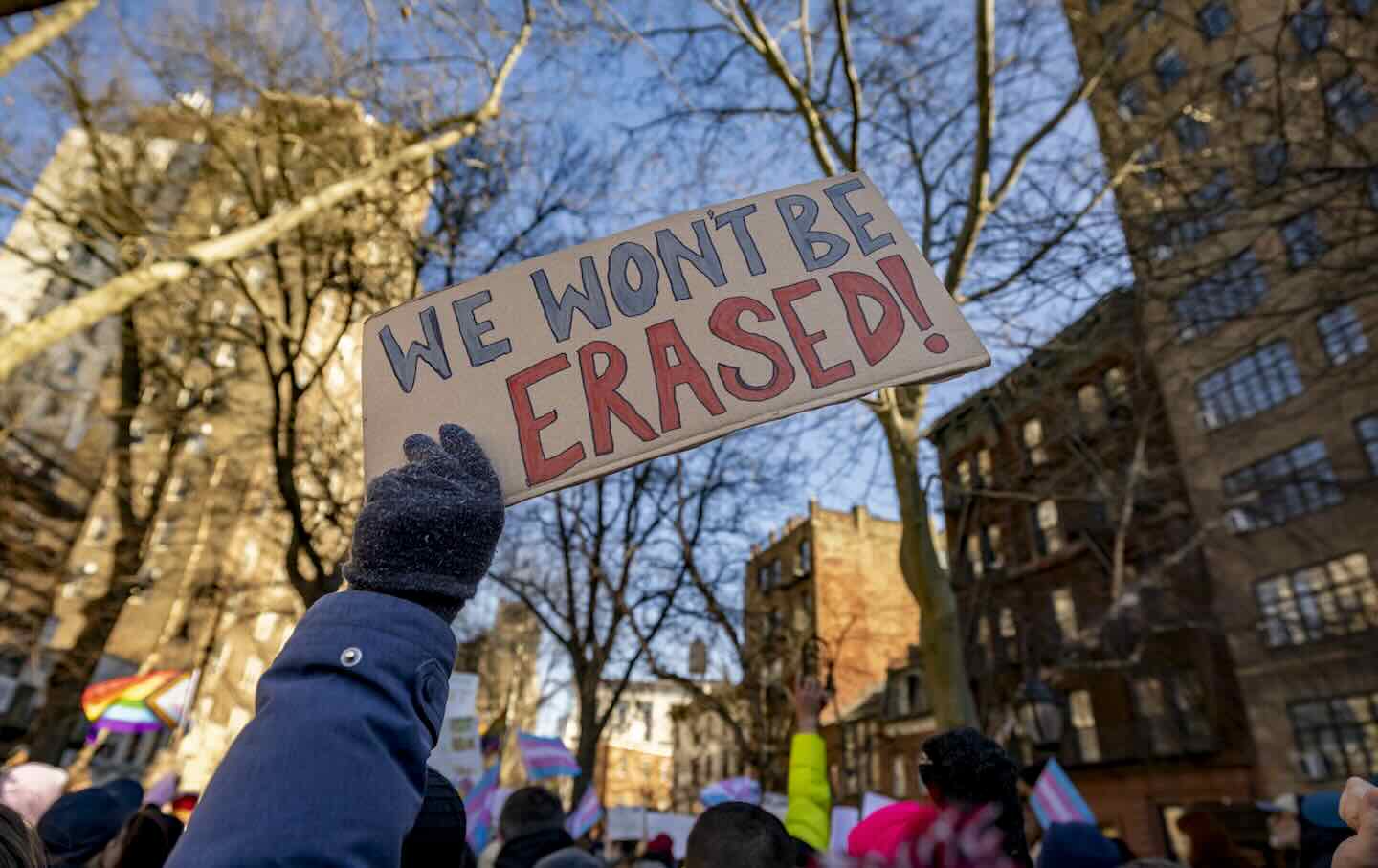A protester holds up a sign with the words “We won't be erased” as activists, politicians, and others gather for a rally outside of the Stonewall Inn after the National Park Service eliminated references to transgender people from its Stonewall National Monument website on February 14, 2025, in New York City.