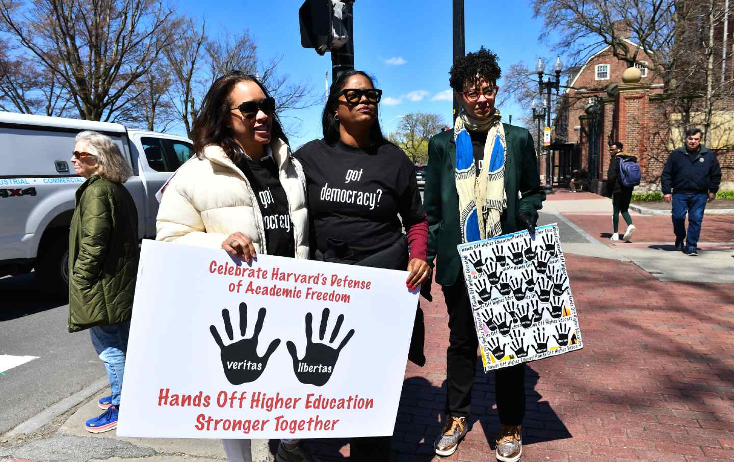 Demonstrators with signs stand around the John Harvard Statue in Harvard Yard after a rally was held against President Donald Trump's attacks on Harvard University.