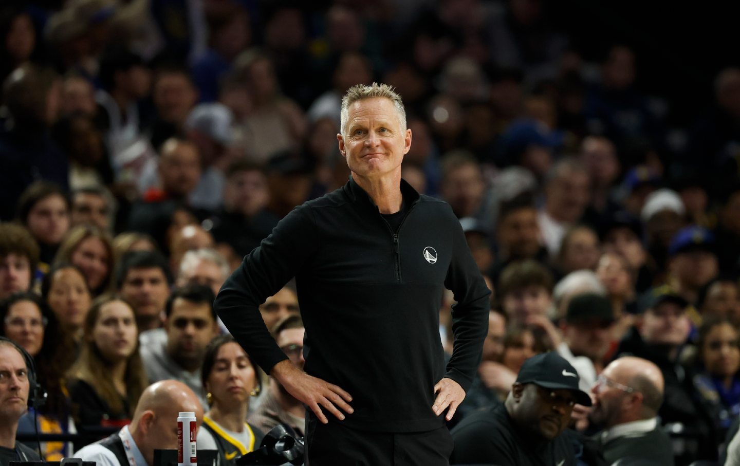 Head coach Steve Kerr of the Golden State Warriors smiling with hands on hips in front of game watchers at at the Moda Center.