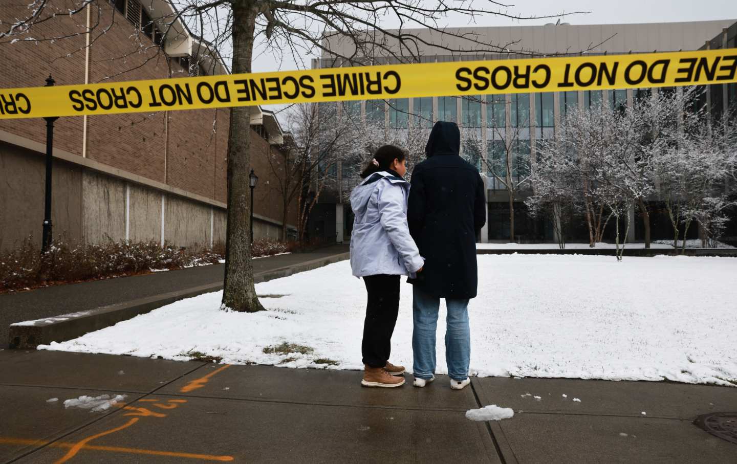People pause outside of the engineering and physics building at Brown University, the site of a mass shooting yesterday that left at least two people dead and nine others injured, on December 14, 2025 in Providence, Rhode Island.