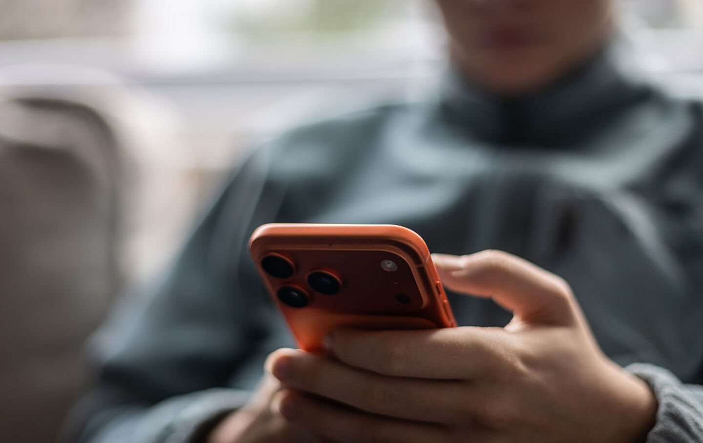 A boy looks at an iPhone screen displaying various social media apps on December 13, 2025.