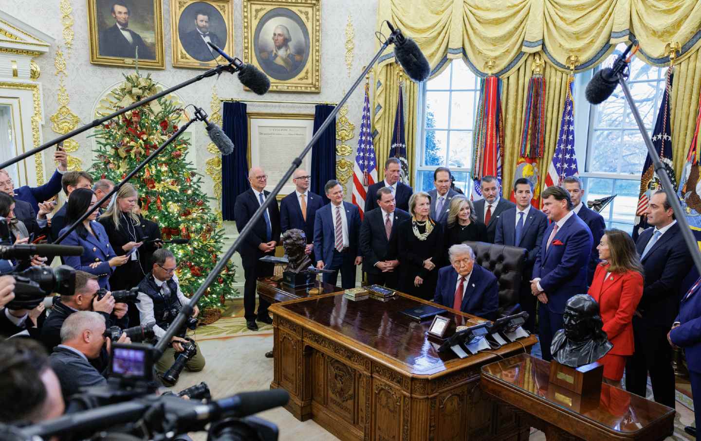 Trump surrounded by media in the oval office.