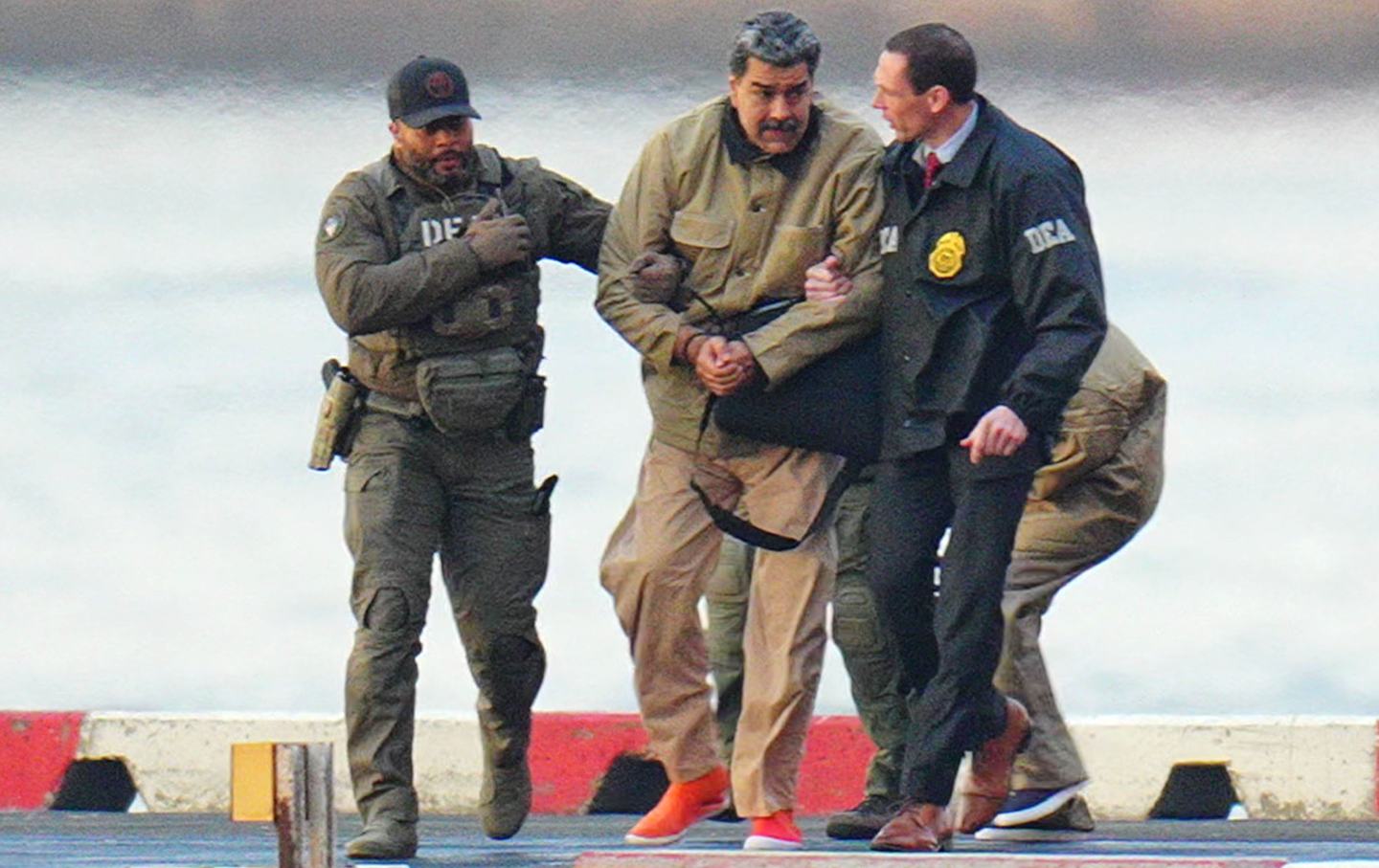 Nicolas Maduro and his wife, Cilia Flores, are seen in handcuffs after landing at a Manhattan helipad, escorted by heavily armed Federal agents as they make their way into an armored car en route to a federal courthouse in Manhattan on January 5, 2026 in New York City.