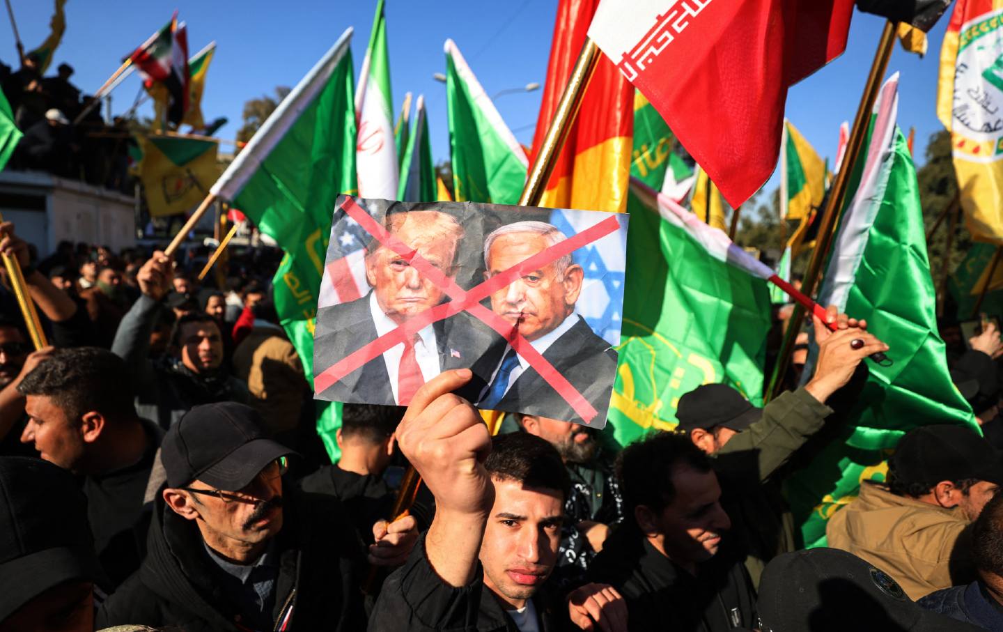 A protester holds up crossed out portraits of US President Donald Trump and Israeli Prime Minister Benjamin Netanyahu during a demonstration near the Iranian embassy in Baghdad on January 16, 2026, against Israel and recent US threats of military action in Iran, and in support of the Iranian regime and its supreme leader.
