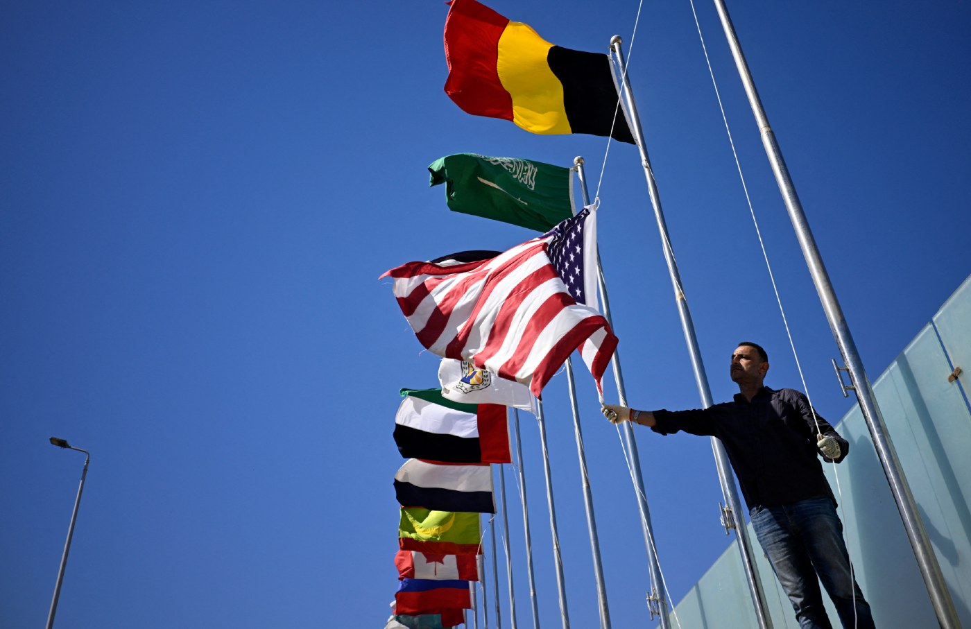 A municipal employee raises the US flag at Sharm el-Sheikh as the town prepares to receive foreign leaders on October 11, 2025.