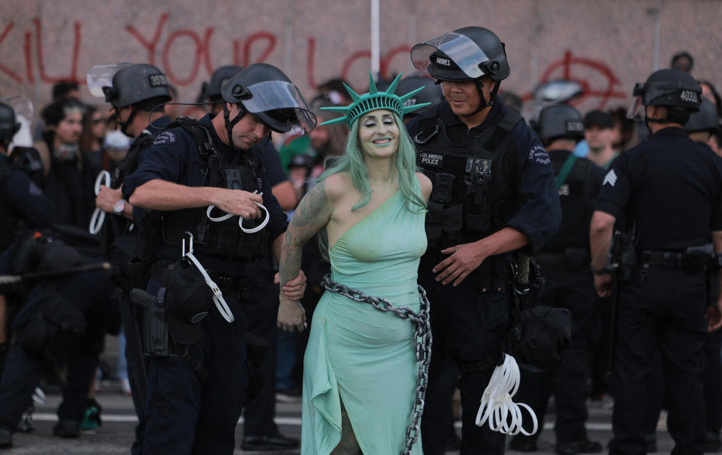 LAPD officers arrest a protester dressed as Lady Liberty in chains following clashes near the Metropolitan Detention Center during the “No Kings” national day of protest in Los Angeles on March 28, 2026.