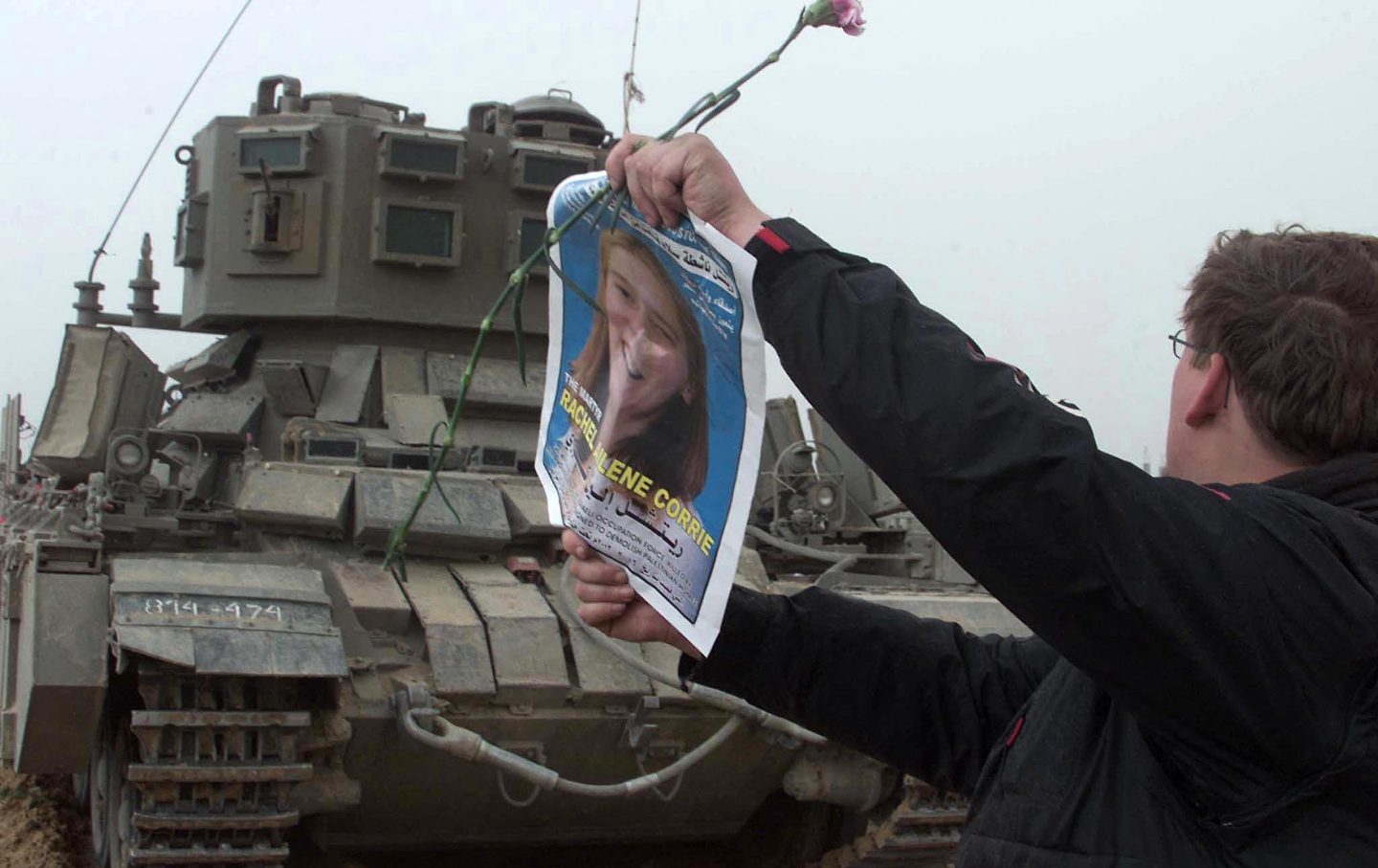 A foreign member of the "International Solidarity Movement" waves a picture of US peace activist Rachel Corrie in front of an Israeli tank during a demonstration held at the site where Corrie was killed near the borde