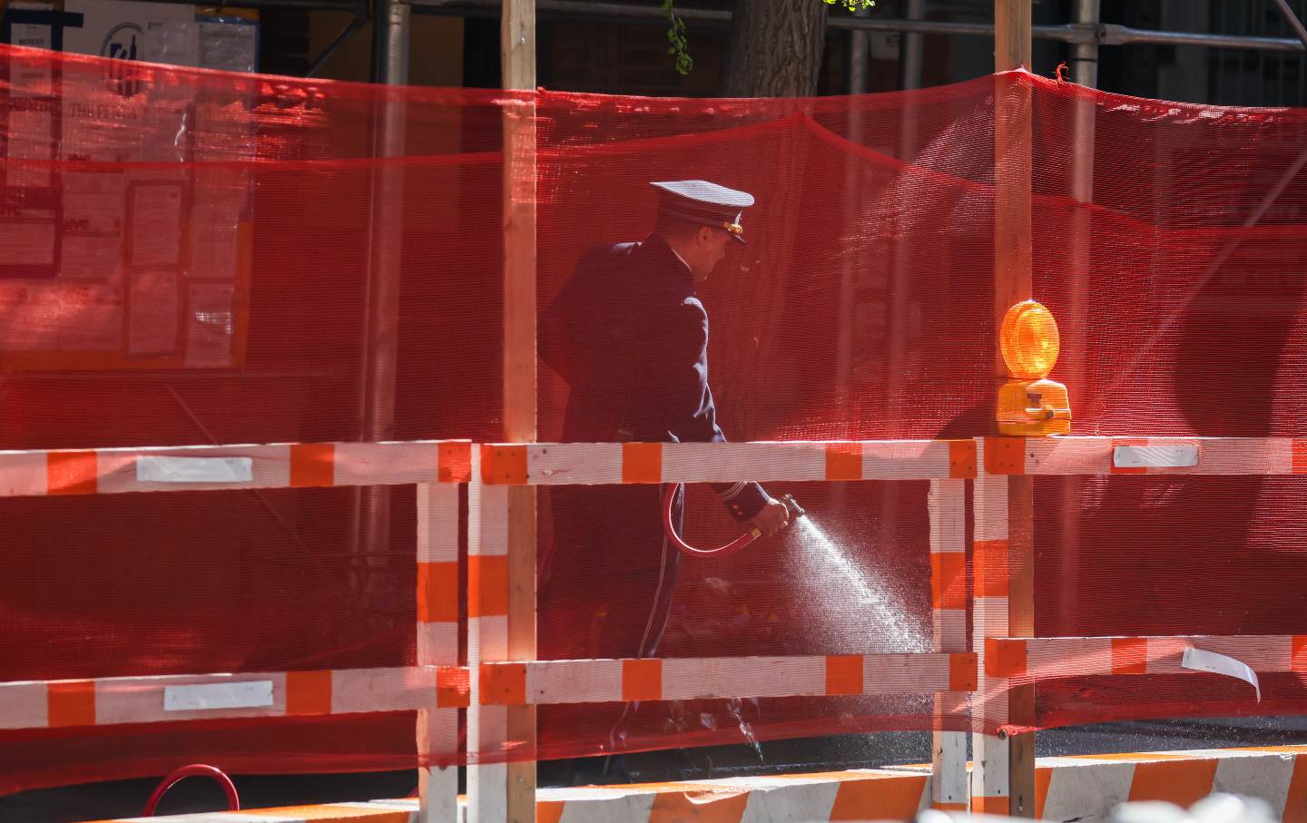 A doorman hoses down a sidewalk outside a building in the Upper East Side neighborhood of New York City, on April 14, 2026.