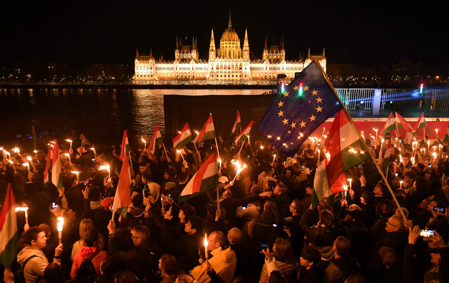 Supporters of the pro-European conservative TISZA party celebrate during the election night on the banks on the river Danube with the Parliament building in the background, in Budapest after the general election in Hungary, on April 12, 2026.