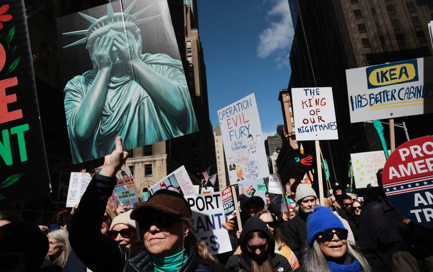 Protesters hold signs as they participate in the third nationwide 'No Kings' protest in Manhattan on March 28, 2026, in New York City.