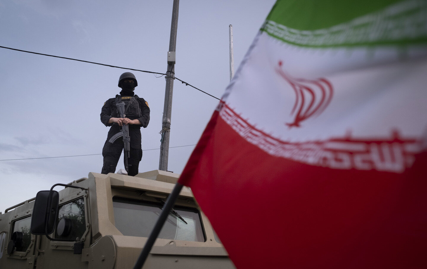 An armed Iranian police officer stands guard on an armored vehicle, monitoring the area during a state-run religious rally in downtown Tehran.