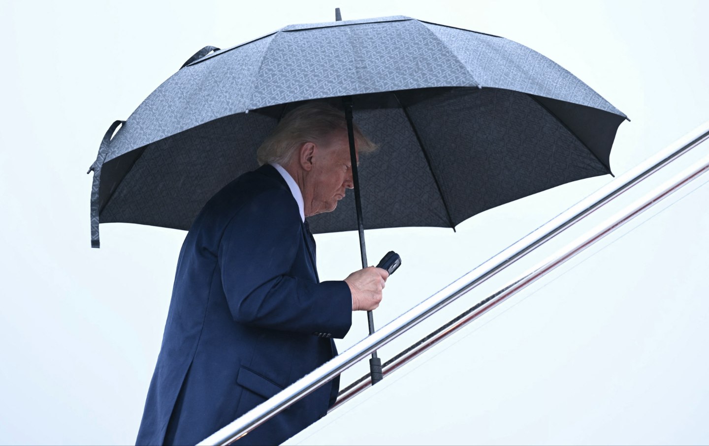 US President Donald Trump holds an umbrella as he boards Air Force One at Joint Base Andrews in Maryland, on May 22, 2026.