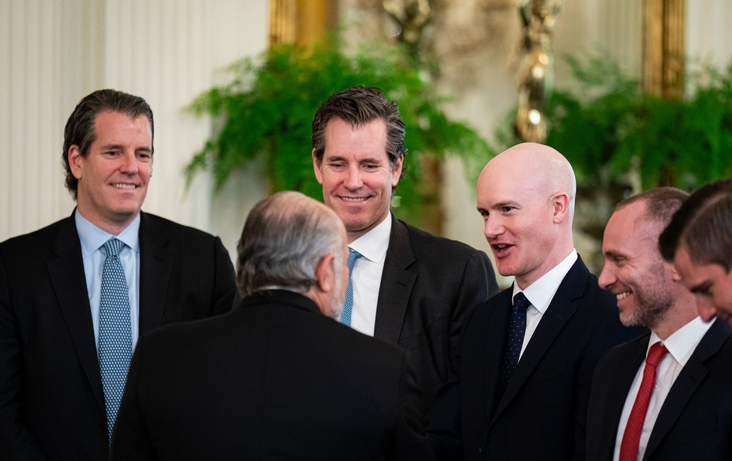 From left: Tyler Winklevoss, cofounder and chief executive officer of Gemini Trust Co.; Cameron Winklevoss, cofounder and president of Gemini Trust Co.; Brian Armstrong, chief executive officer of Coinbase Global Inc.; and Paolo Ardoino, chief executive officer of Tether Holdings Ltd., speak with Howard Lutnick, US commerce secretary, during a signing ceremony for the GENIUS Act in the East Room of the White House in Washington, DC, on July 18, 2025.
