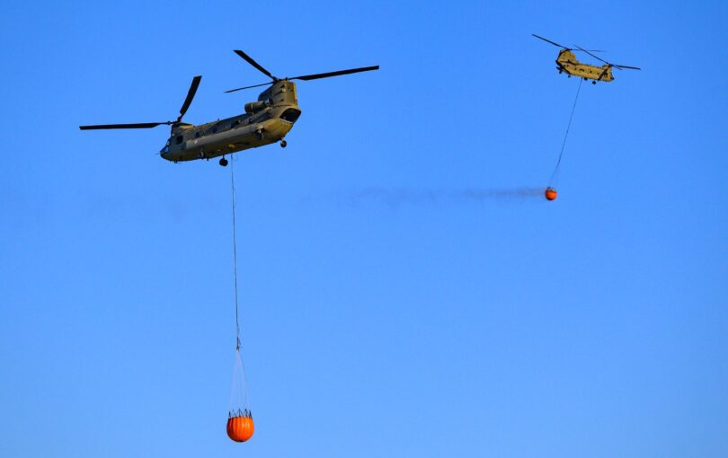 A transport helicopter of the Dutch Royal Air Force carrying a water bucket for extinguishing wildfires in nature, loads water into the bucket to put out a wildfire in the Veluwe nature reserve on April 29, 2026.