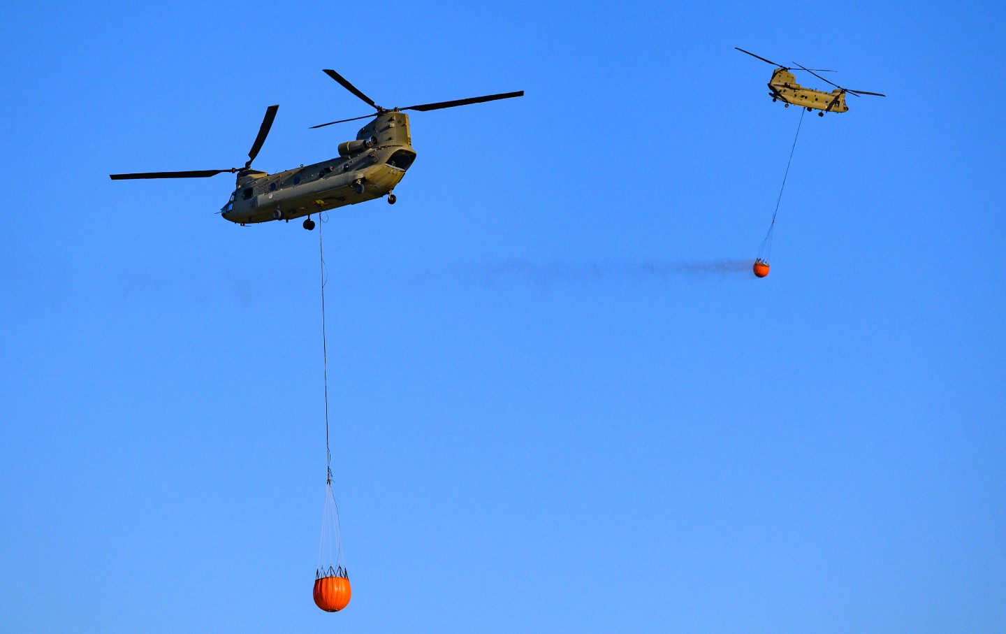A transport helicopter of the Dutch Royal Air Force carrying a water bucket for extinguishing wildfires in nature, loads water into the bucket to put out a wildfire in the Veluwe nature reserve on April 29, 2026.