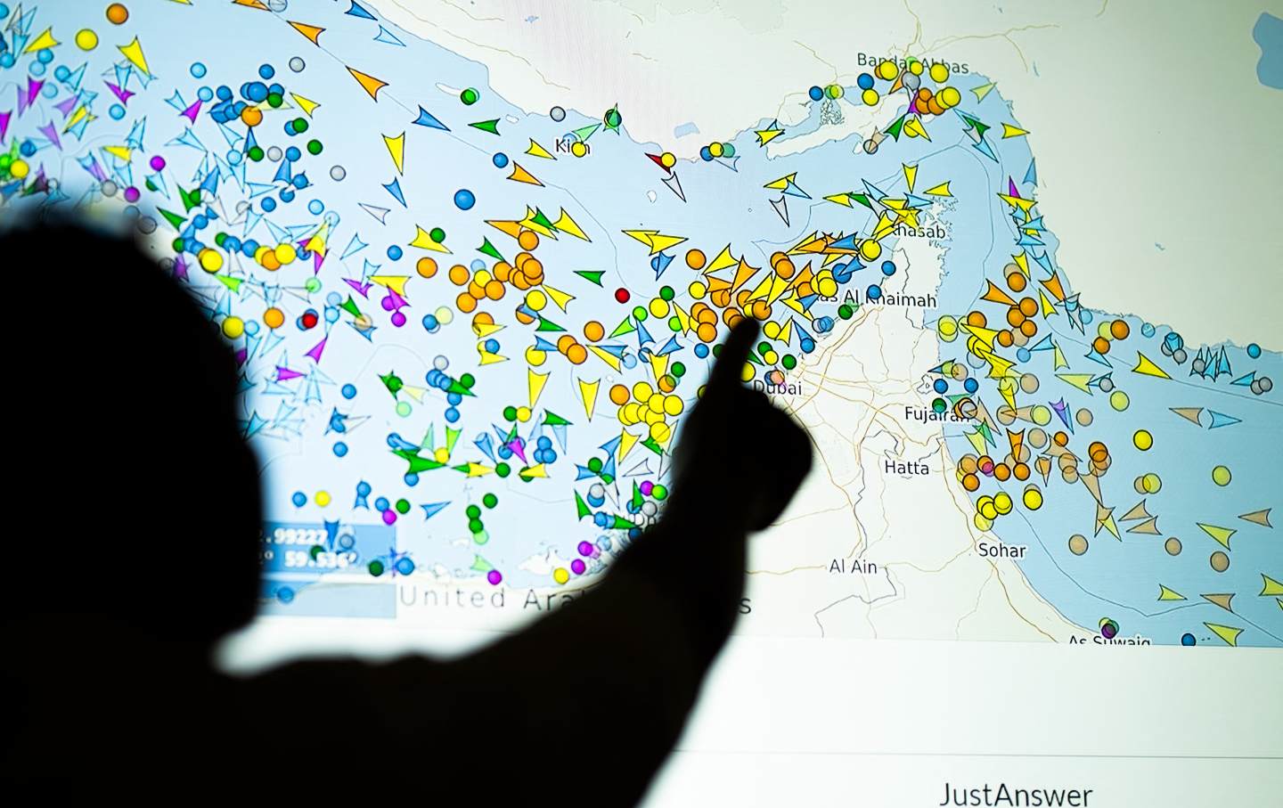 A photo illustration taken in Nicosia shows a person in front of a large screen displaying vessel movements in the Strait of Hormuz on a ship-tracking website, on May 4, 2026.