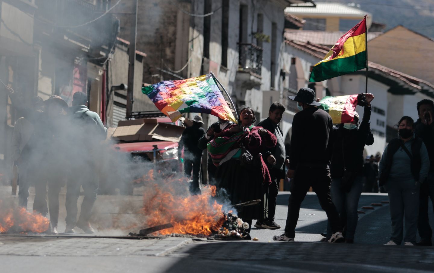 Smoke is rising from a fire lit in the street as protesters with flags call for the resignation of Bolivian President Rodrigo Paz after weeks of protests and blockades in La Paz, Bolivia, on June 10, 2026.