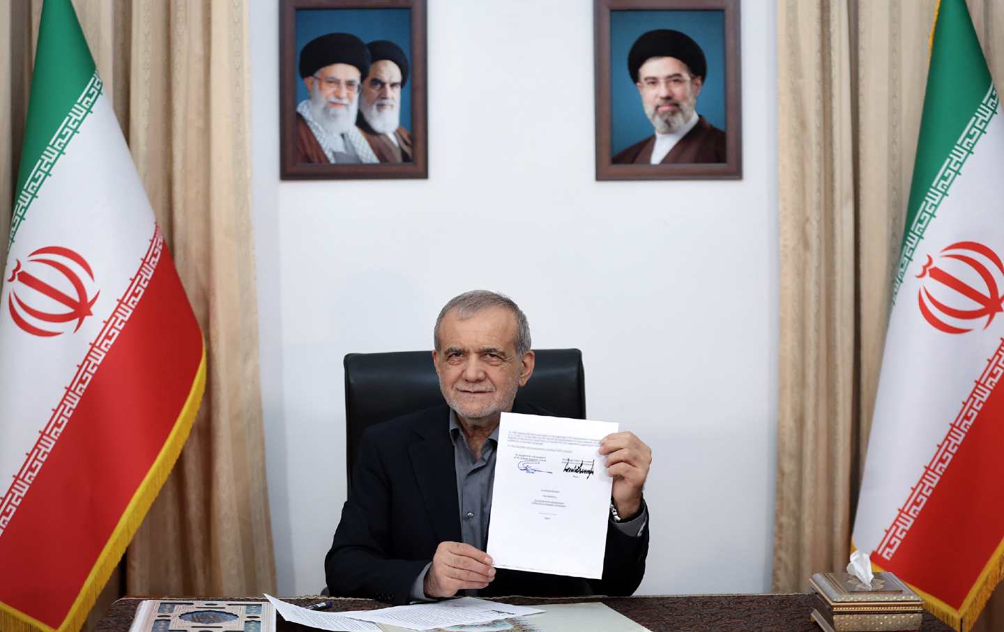 Iranian President Masoud Pezeshkian displays his signed copy of the memorandum of understanding establishing a framework to end the US war with Iran