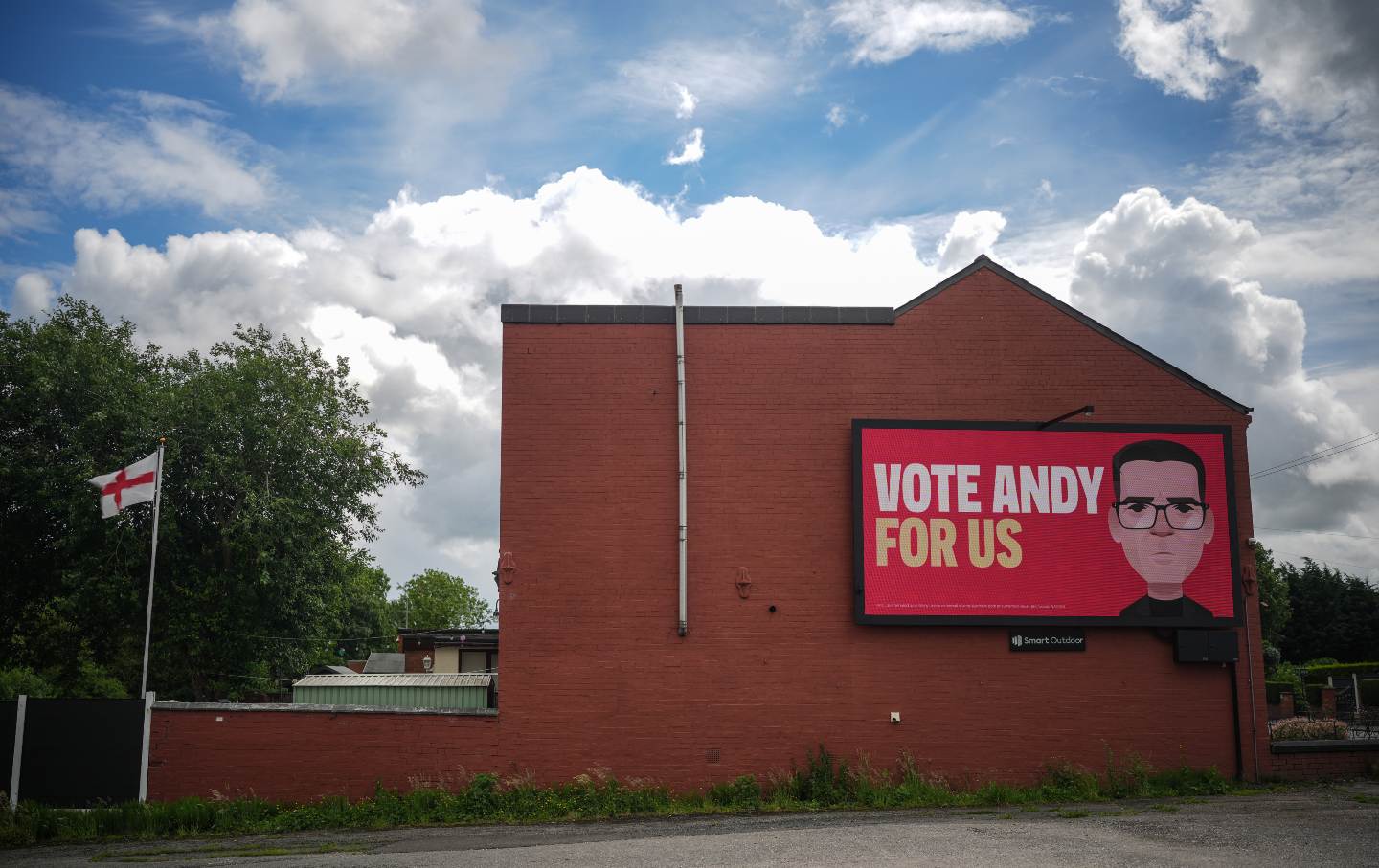A video screen declaring “VOTE ANDY FOR US” and depicting Andy Burnham adorns the side of a home in Ashton-in-Makerfield, England, on June 10, 2026.