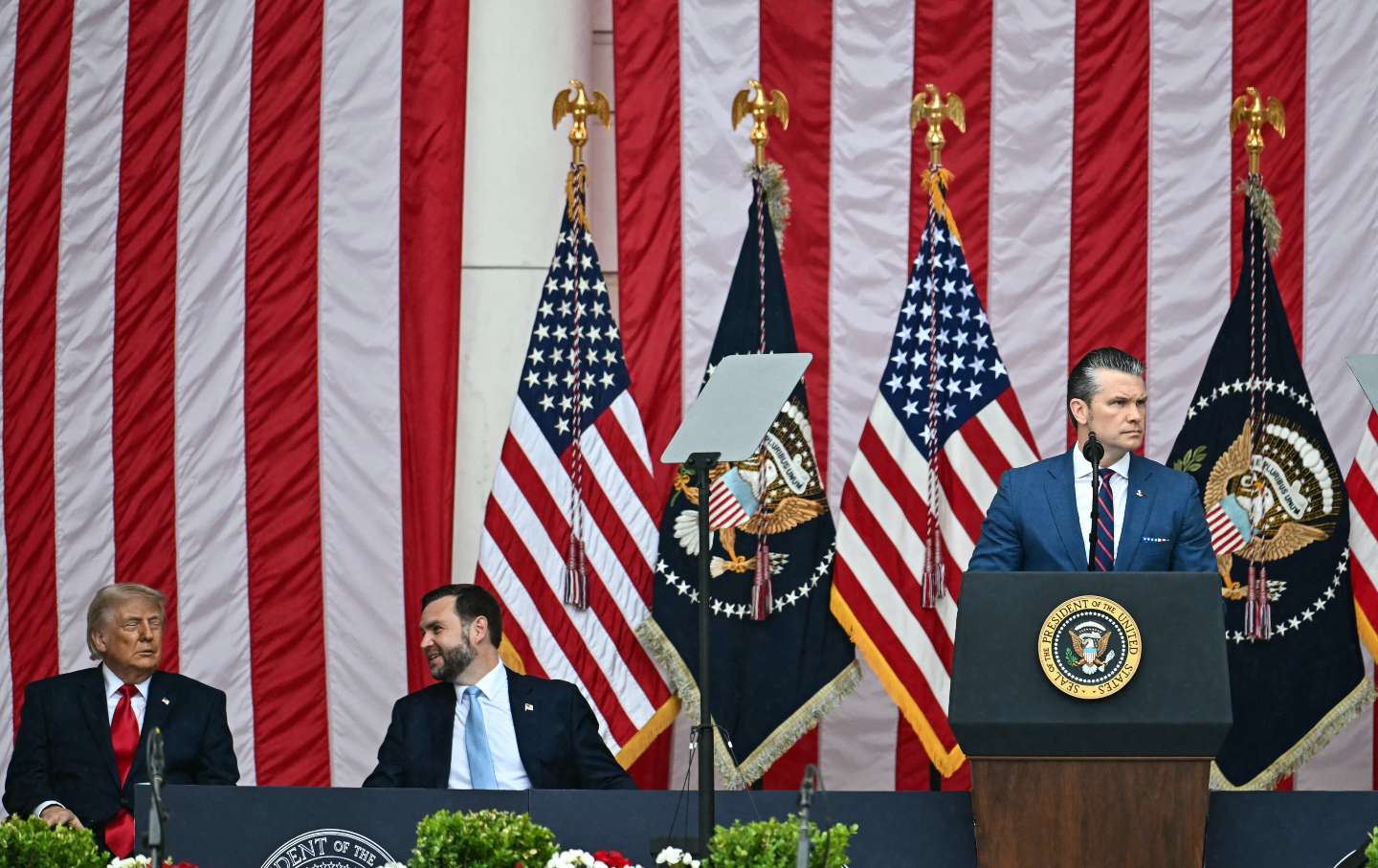 US President Donald Trump sits with Vice President JD Vance as Defense Secretary Pete Hegseth delivers remarks during the National Memorial Day Observance at the Memorial Amphitheater in Arlington National Cemetery in Arlington, Virginia, on May 25, 2026.