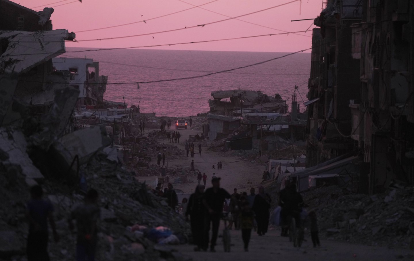 Palestinians walk between destroyed buildings in Gaza City, Wednesday, June 3, 2026.