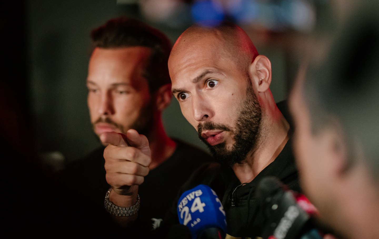 Andrew Tate and his brother Tristan Tate talk to the media outside their residence on March 23, 2025 in Bucharest, Romania.