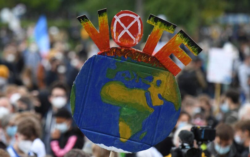 A protester holds up an Earth-shaped sign reading “Vote.”