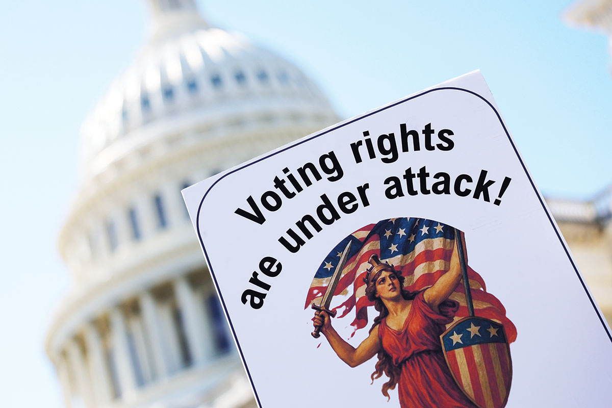 A protester waves a warning against the SAVE America Act, which would require voter IDs, among other restrictions.
