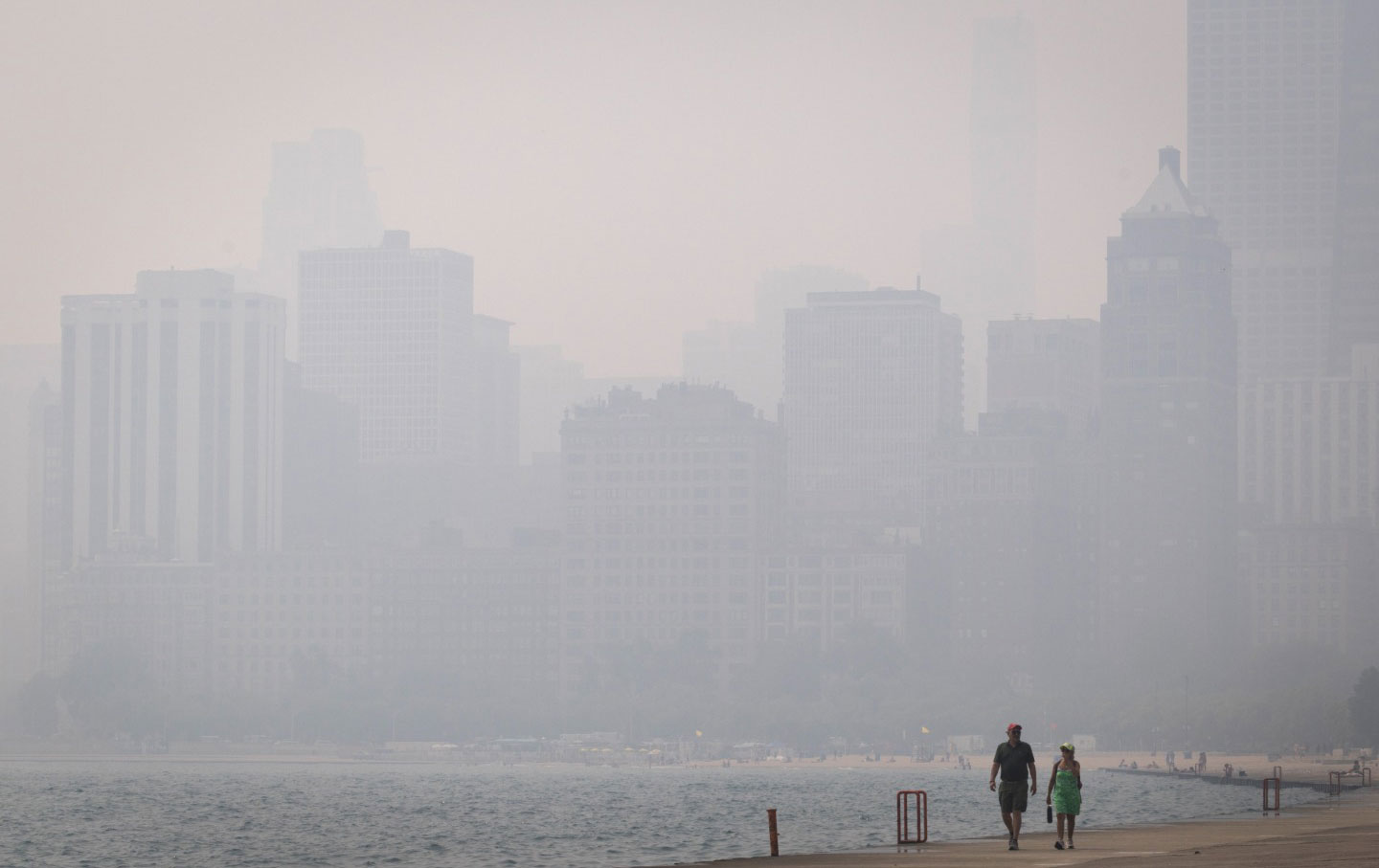 A couple walks along Lake Michigan as smoke from Canadian wildfires blankets Chicago, Illinois, on July 16, 2026.